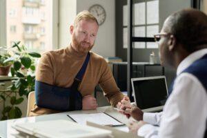 Man with his arm in a sling speaking with a lawyer about how long short-term disability lasts.
