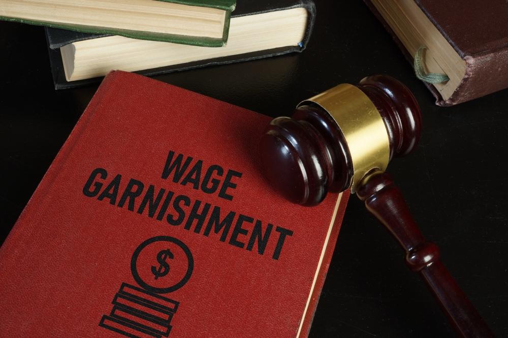 A judge’s gavel on top of a book titled “Wage Garnishment” that says if long term disability can be garnished