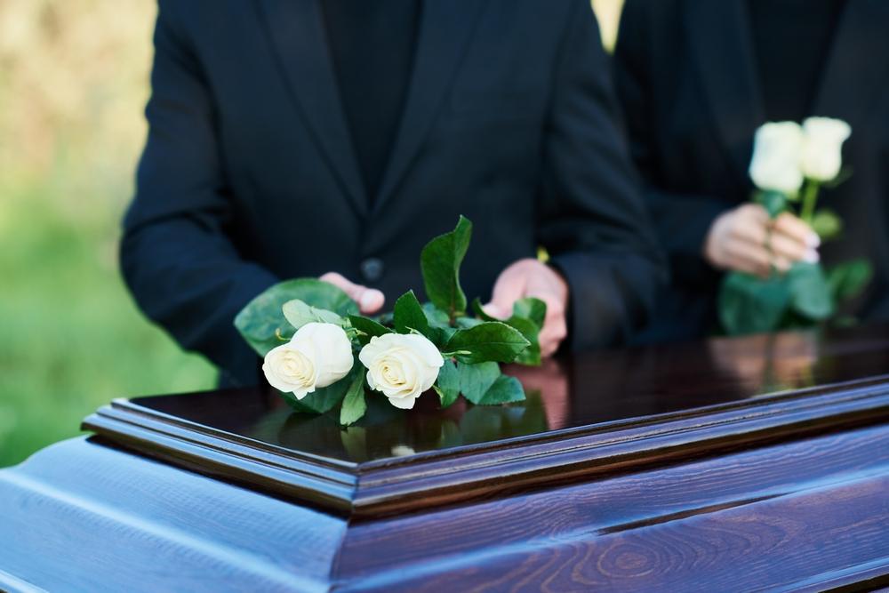 A man putting a rose on top of a coffin. A lawyer can explain how long you have to claim life insurance.