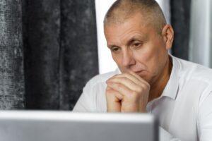 A man sitting at his computer, wondering if he should get long-term disability in Baton Rouge.