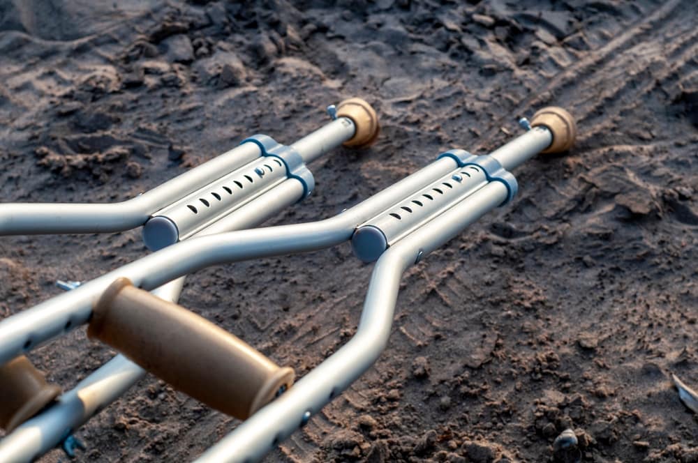 Pair of aluminum crutches lying on muddy ground